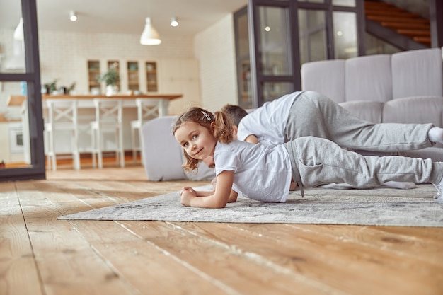 Cheerful little girl doing workout with family at home