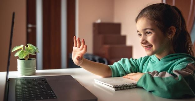 Cheerful little girl in front of laptop screen chatting online