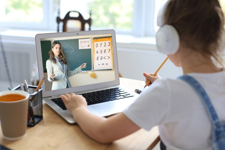Photo cheerful little girl girl in headphones using laptop studying through online elearning system