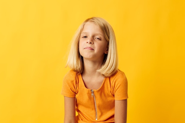 陽気な小さな女の子の手のジェスチャーと楽しい黄色の背景