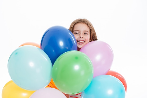 Cheerful little girl holding colorful balloons and having fun