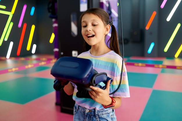 Веселая маленькая девочка держит очки виртуальной реальности