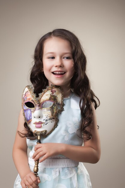 Photo cheerful little girl posing with carnival mask