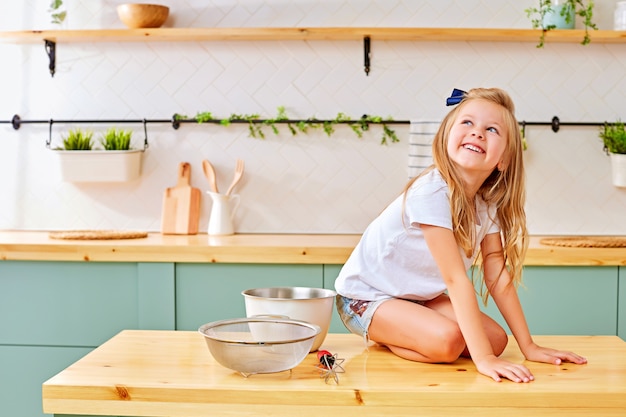 Cheerful little girl sitting on kitchen table