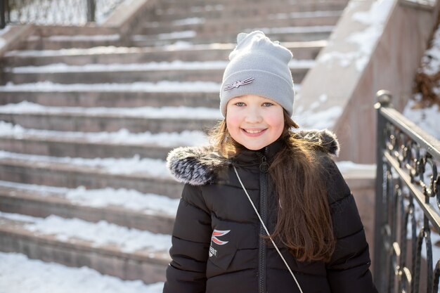 Cheerful little girl on a walk in the park in winter