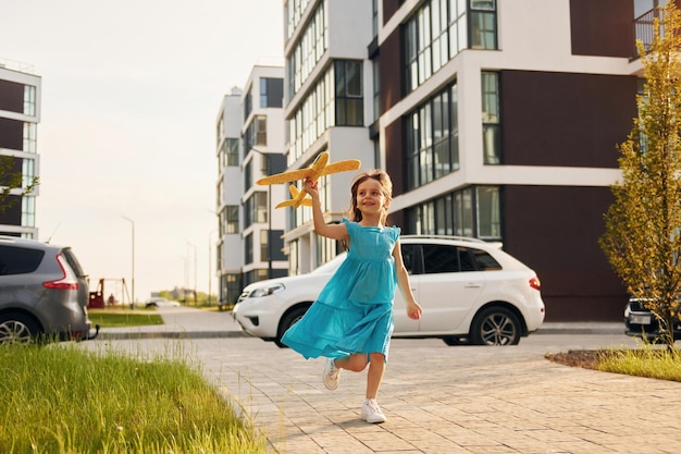 Cheerful little girl walking outdoors in the city in dress