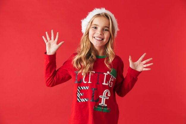 Bambina allegra che indossa il costume di natale in piedi isolato, celebrando