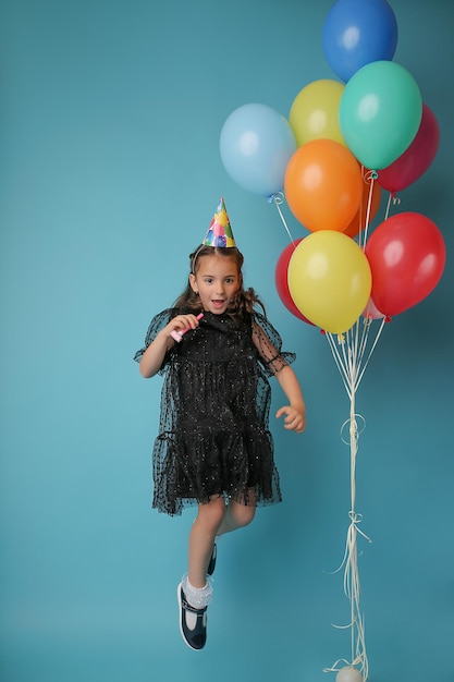 Bambina allegra con palloncini sullo sfondo di colore blu buona festa di compleanno