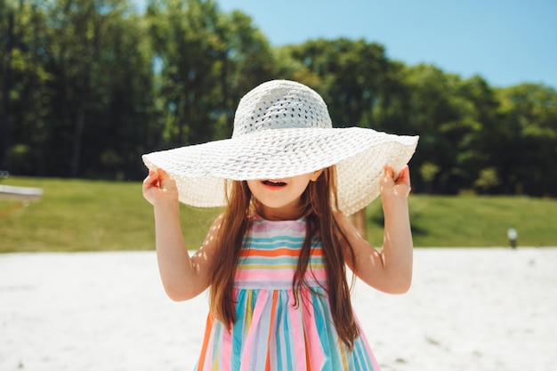 해변에서 여름 모자를 쓰고 다운 증후군을 가진 쾌활한 어린 소녀