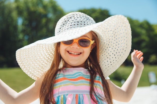 Cheerful little girl with down syndrome in a summer hat on the beach