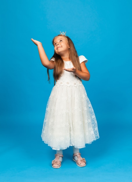 Bambina allegra con i capelli lunghi in un abito da principessa e con una corona.