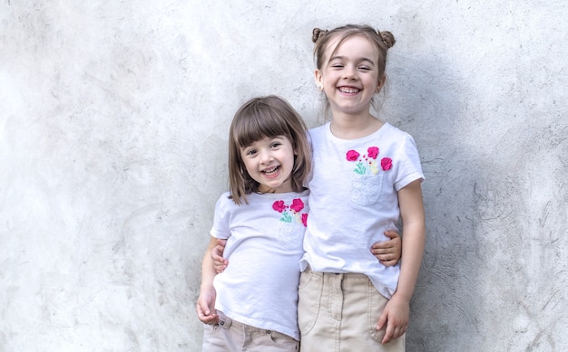 Cheerful little girls on gray textured wall