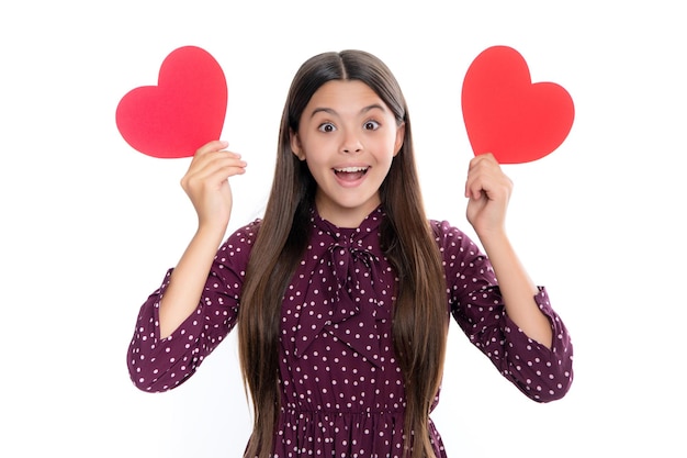 Cheerful lovely romantic teen girl hold red heart symbol of love for valentines day isolated on white background Portrait of emotional amazed excited teen girl