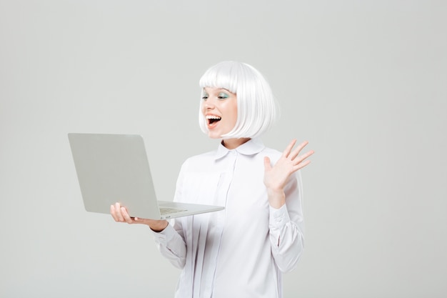 Cheerful lovely young woman standing and using laptop