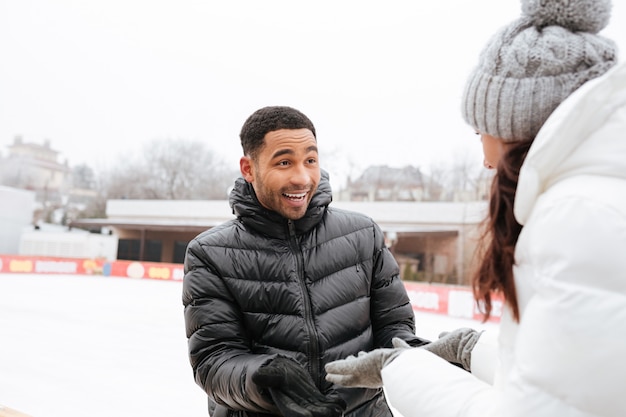 Cheerful loving couple skating at ice rink outdoors.