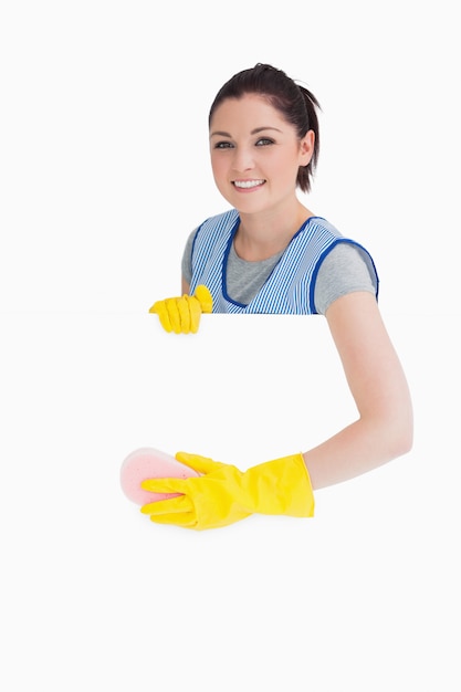 Cheerful maid washing with a sponge