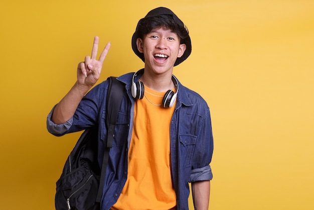 Веселый студент-мужчина, показывающий два пальца в знак приветствия мира в обычной одежде.
