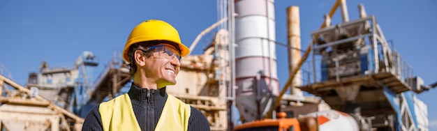 Cheerful male engineer standing outdoors at industrial site