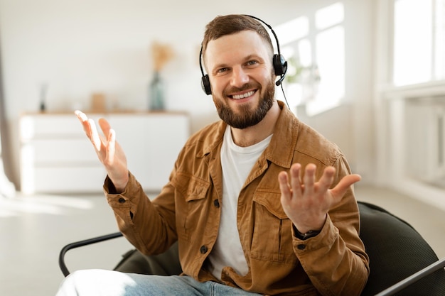 Cheerful male freelancer making video call wearing headset at home