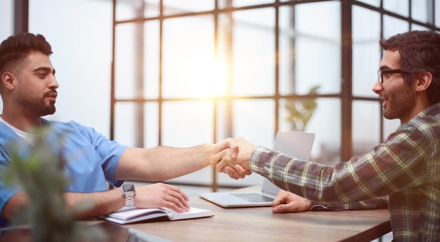 Cheerful male patient and doctor shaking hands