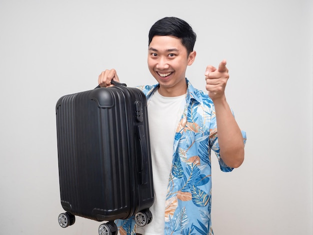 Cheerful man beach shirt hold luggage smiling point finger at you