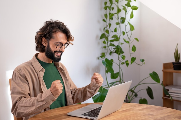 Cheerful man celebrates a success at work with his fists happy man reads good news in the laptop