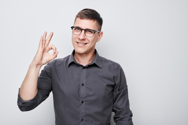Photo cheerful man in checkered shirt making ok gesture smiling at camera on white background