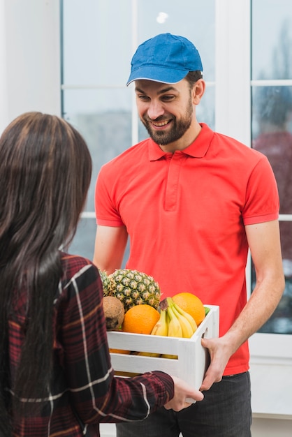 Foto uomo allegro che consegna frutti alla donna