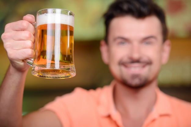 Cheerful man drinking beer at bar.