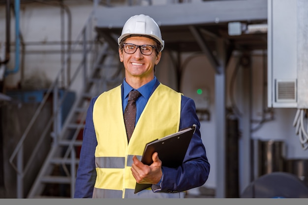 Cheerful man engineer with documents working at factory