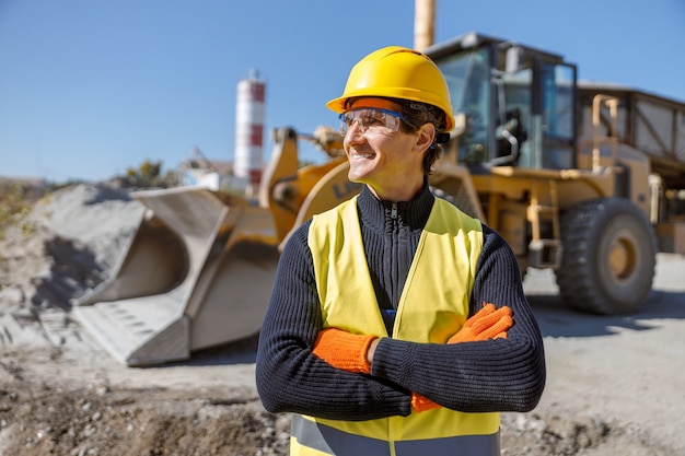 Cheerful man factory worker standing near tractor outdoors