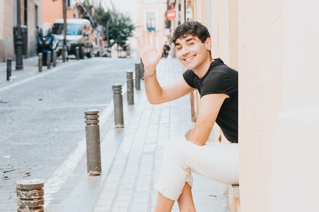 Cheerful man greeting at camera outdoors with copy space. City of madrid. Happy life style concept. Happy with new habits