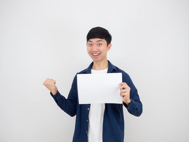 Cheerful man holding empty paper in hand and fist up with happy face and smile on white isolated background