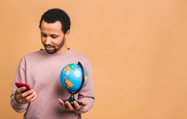 Cheerful man holding the globe with love and care isolated over beige