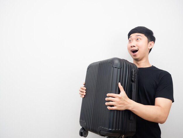 Cheerful man holding luggage feeling excited looking at copy space