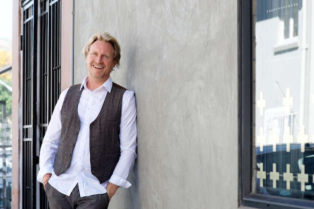 Cheerful man leaning against wall and smiling