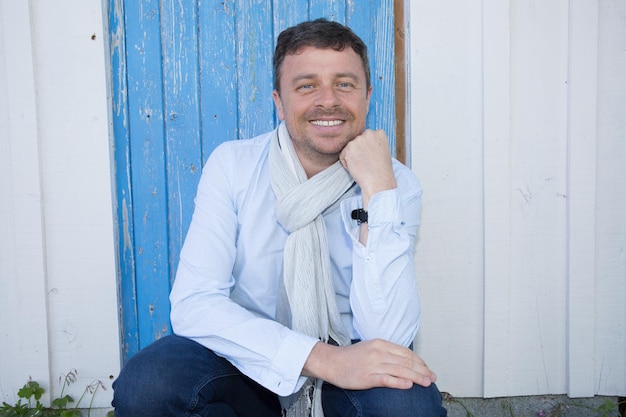 Cheerful man outside sitting in front of blue background