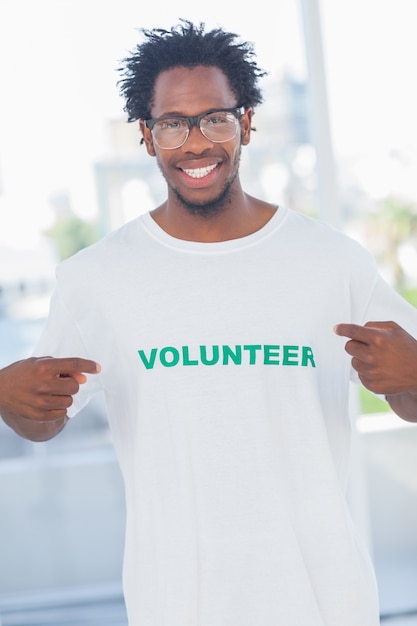 Веселый мужчина, указывая на свою волонтерскую футболку