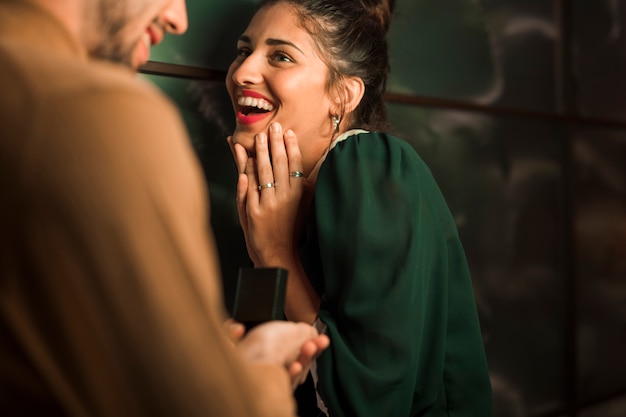 Cheerful man presenting gift in box to young happy woman