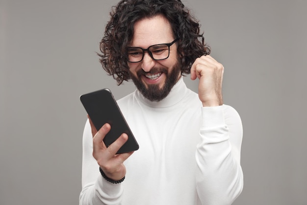 Фото Веселый мужчина читает захватывающее сообщение на смартфоне