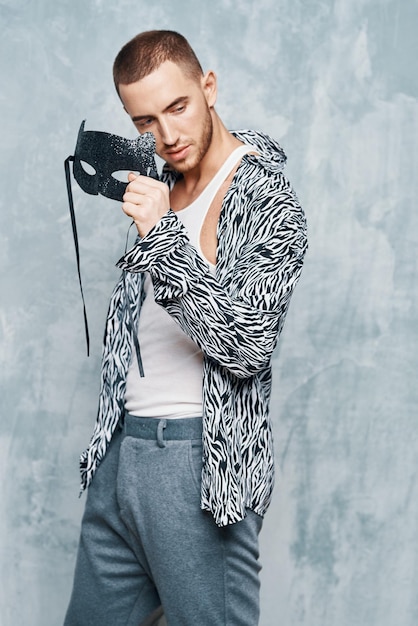 Photo cheerful man in shirt mask near face studio light background