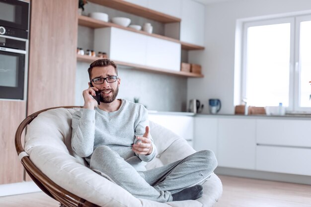 Cheerful man talking on a mobile phone sitting in a comfortable chair