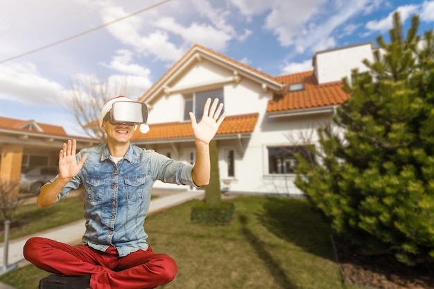 Веселый мужчина в виртуальных очках перед новым домом.
