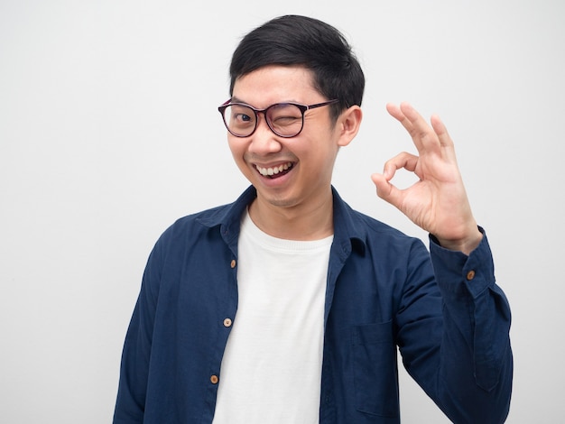 Cheerful man wearing glasses close his eye and make hand ok happy smile