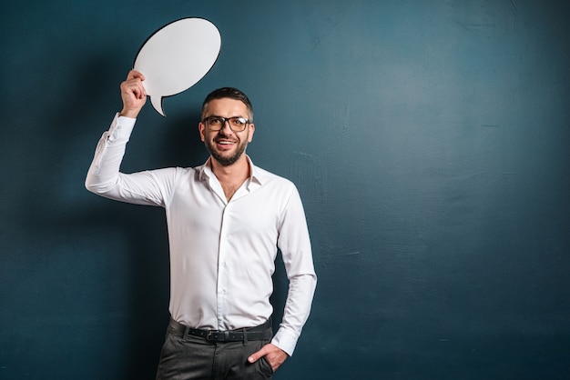 Cheerful man wearing glasses holding speech bubble.