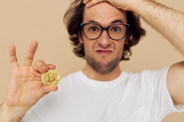 Cheerful man in a white Tshirt with Bitcoin cryptocurrency beige background