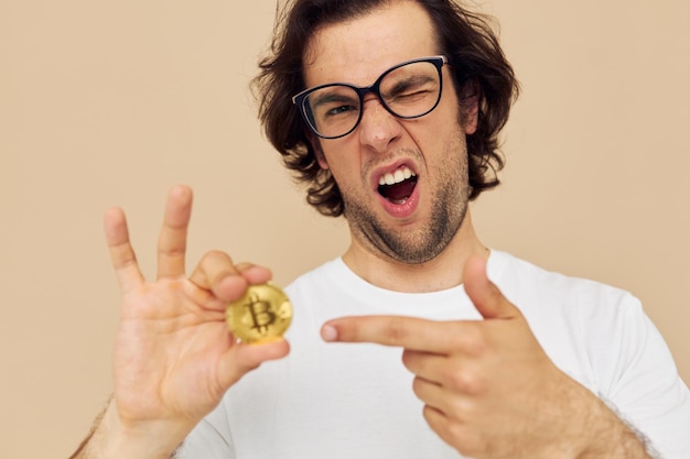 Cheerful man in a white Tshirt with Bitcoin cryptocurrency beige background