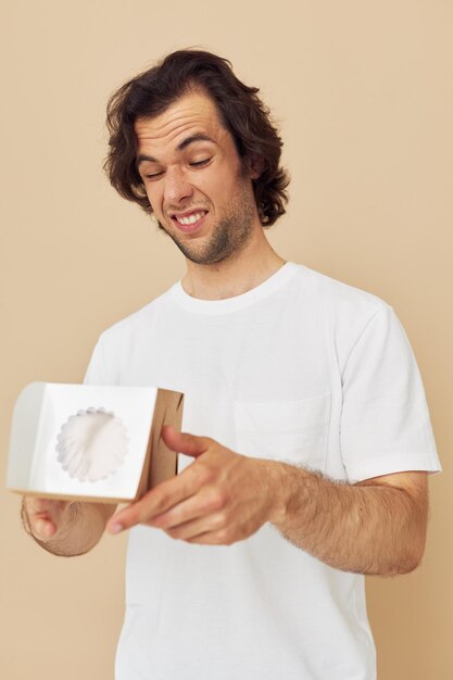 Cheerful man in a white tshirt with a gift box