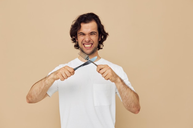 Cheerful man in a white Tshirt with knife with fork Lifestyle unaltered