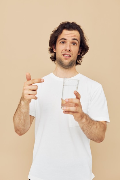 Cheerful man in a white Tshirt with a mug in hand beige background